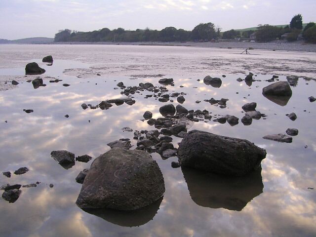 A calm lake with scattered rocks and a distant shoreline.