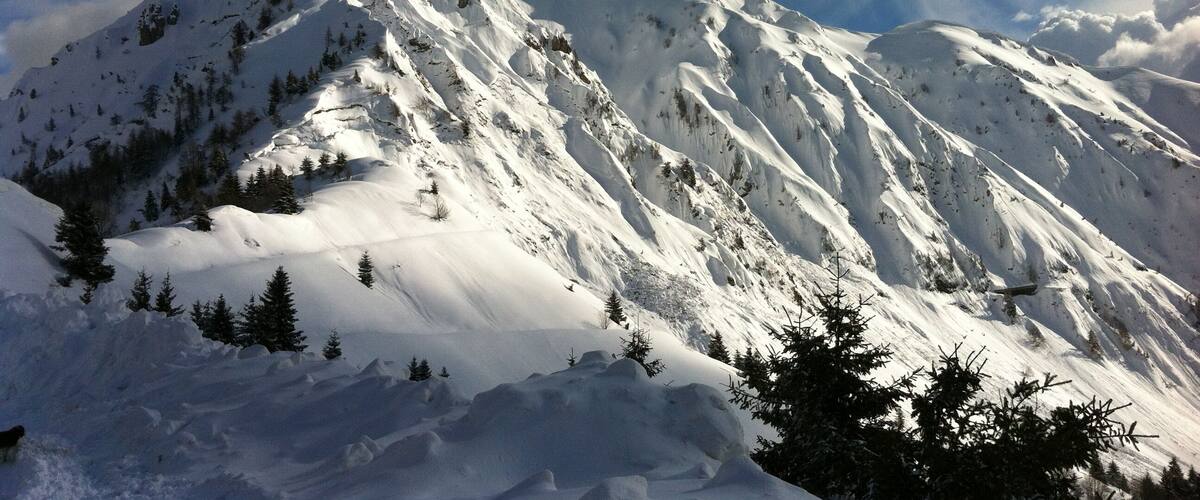 A snow-covered mountain peak with a clear sky and scattered clouds.