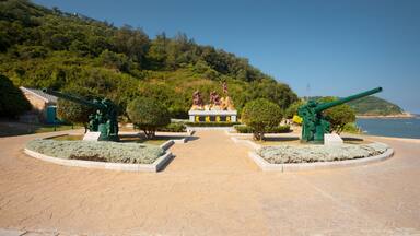 Parque costero con cañones, un monumento y una vista despejada del mar.
