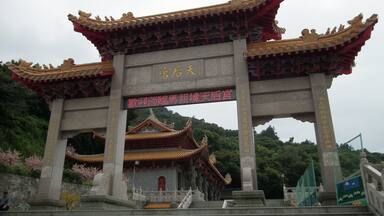 A traditional Chinese gate with ornate architecture, a red and gold roof, and a sign with Chinese characters.