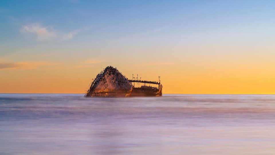 The SS Palo Alto bathed in the warm, golden glow of the sunset at Seacliff State Park Beach.