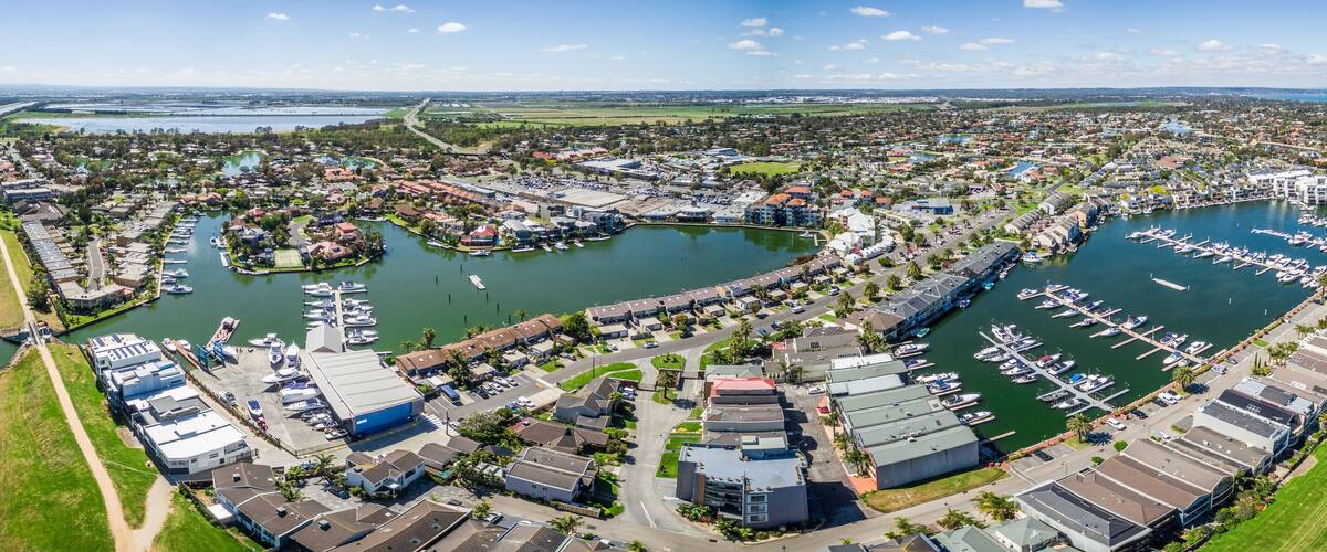Aerial panorama of Patterson River and Patterson Lakes suburb on bright sunny day. Houses nested near water with moored boats nearby. Melbourne, Victoria, Australia