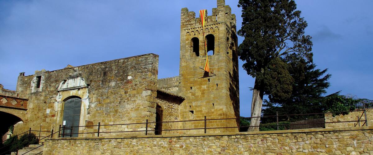 A historic stone building with a tall tower and a flag.