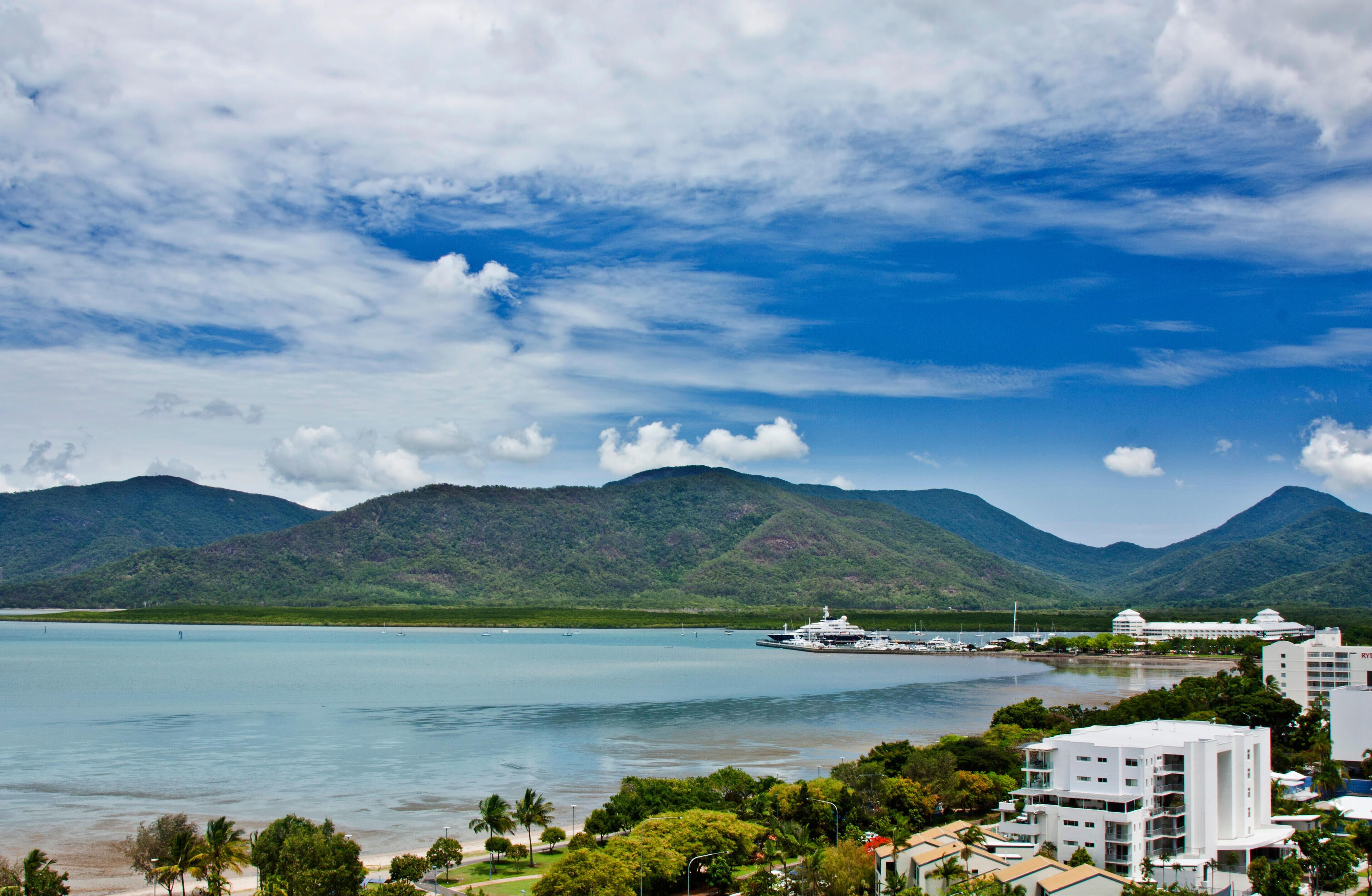 A coastal city with a large body of water, mountains in the background, and a cruise ship docked near the shore.
