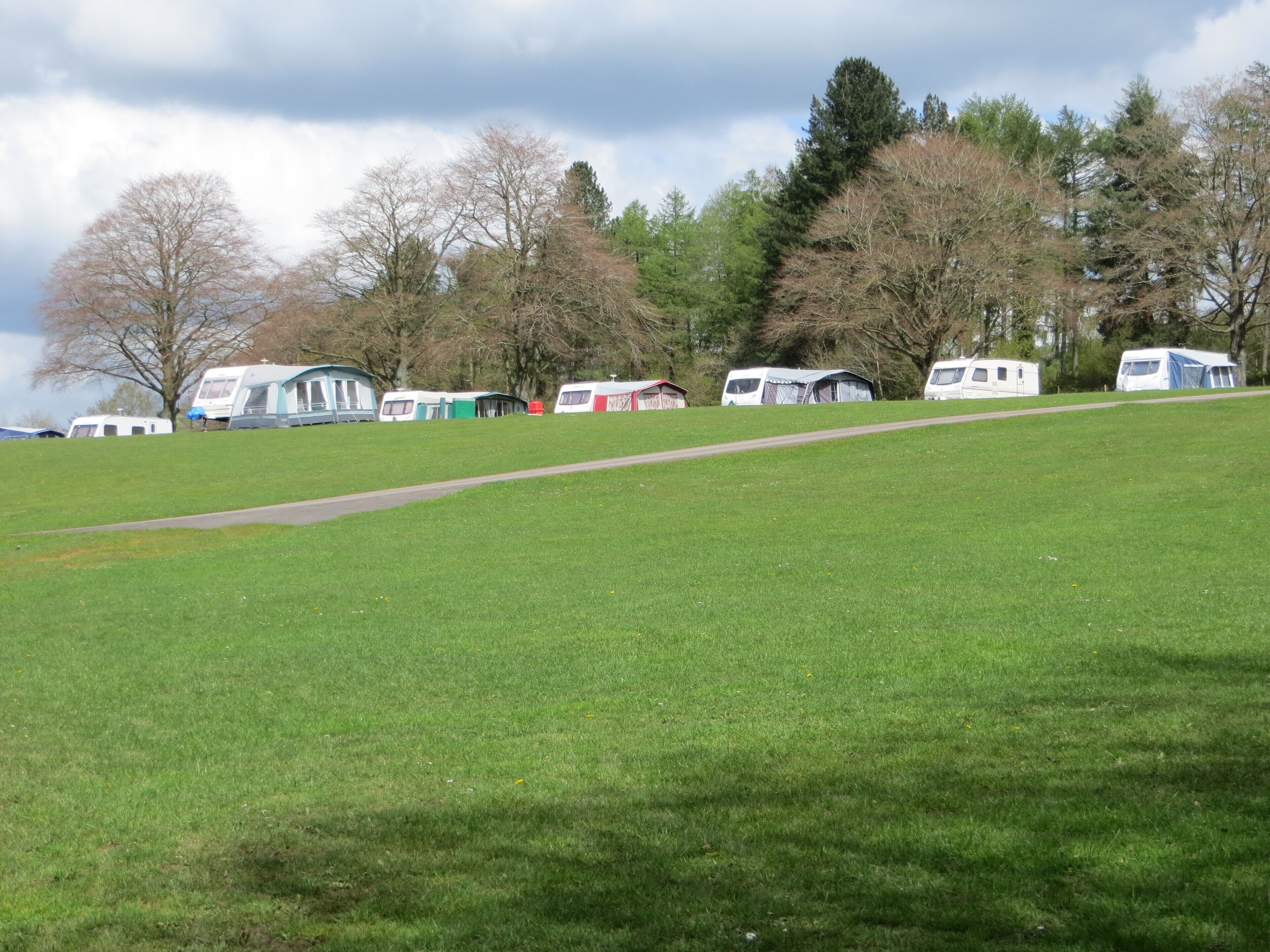 A grassy field with several caravans and a path.