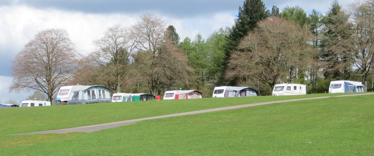 A grassy field with several caravans and a path.
