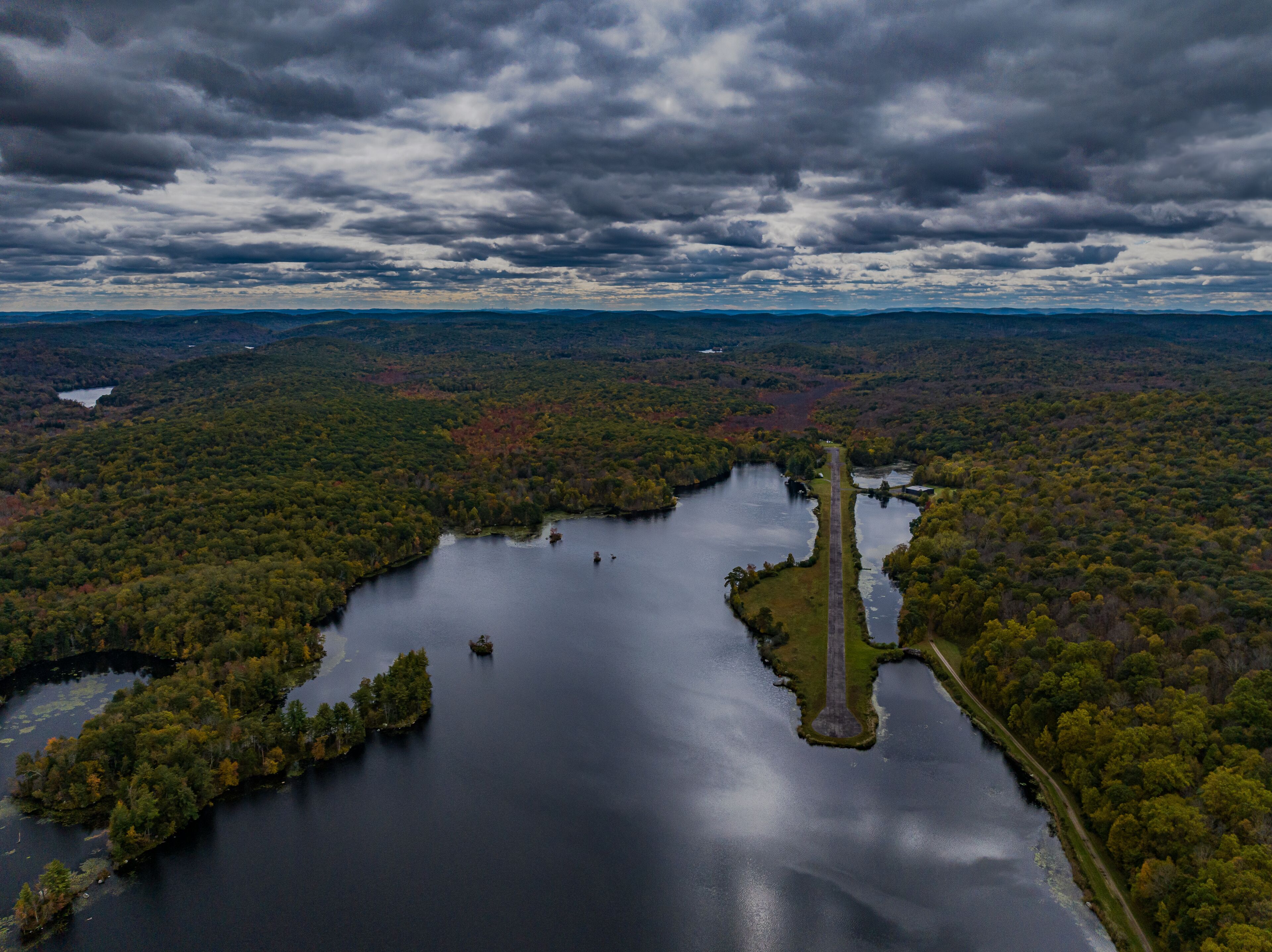 Aerial view of the countryside in Stormville, NY on a cloudy day during the colorful autumn season with a lake in view.