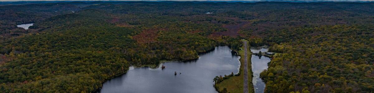 Aerial view of the countryside in Stormville, NY on a cloudy day during the colorful autumn season with a lake in view.