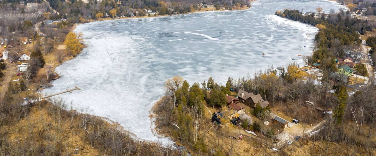 A frozen river with houses and trees along its banks.