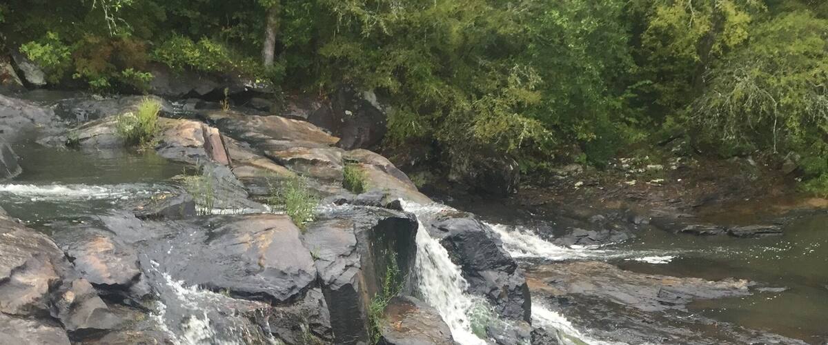 A waterfall cascading over rocks in a forested area.