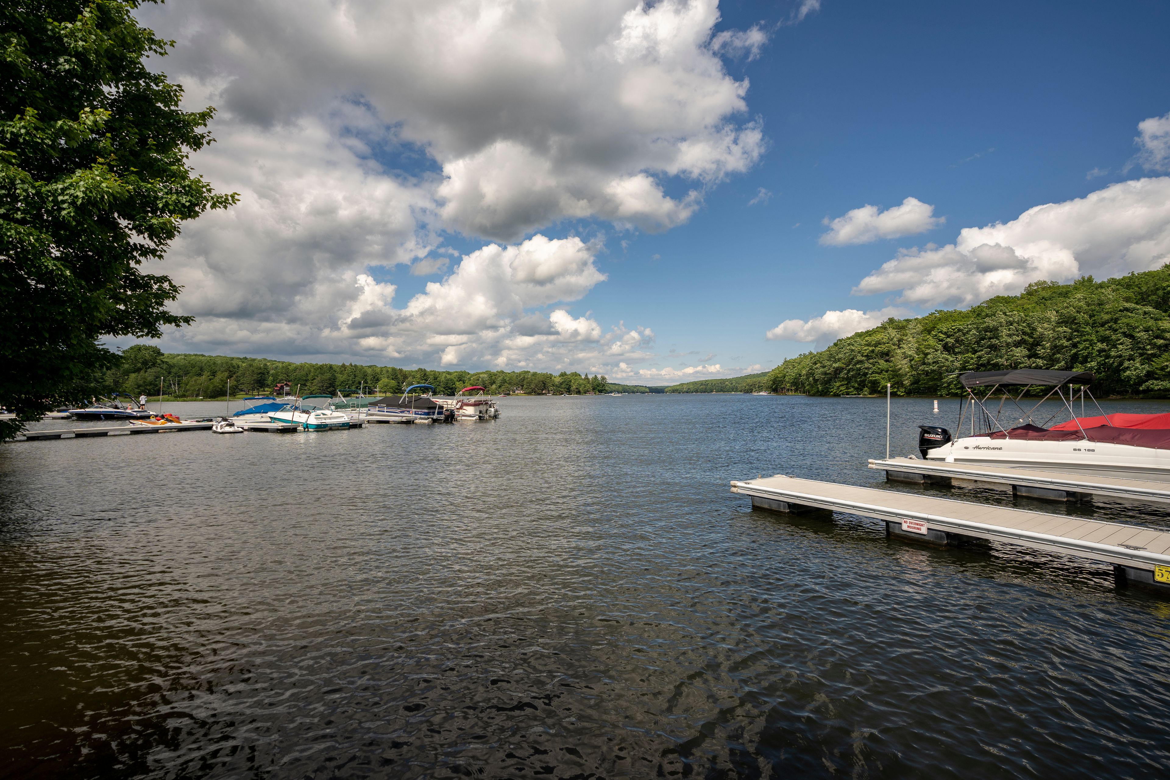 Sun shines on a tranquil dock while boats rock silently in the rippling water of Deep Creek Lake in rural Garrett County, Maryland, USA.