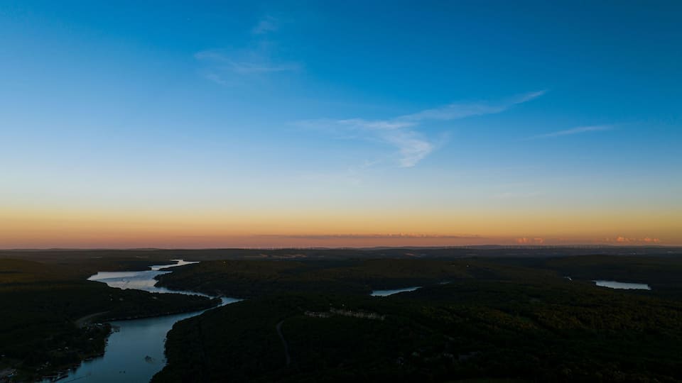 A river winding through a forested landscape with a clear sky.