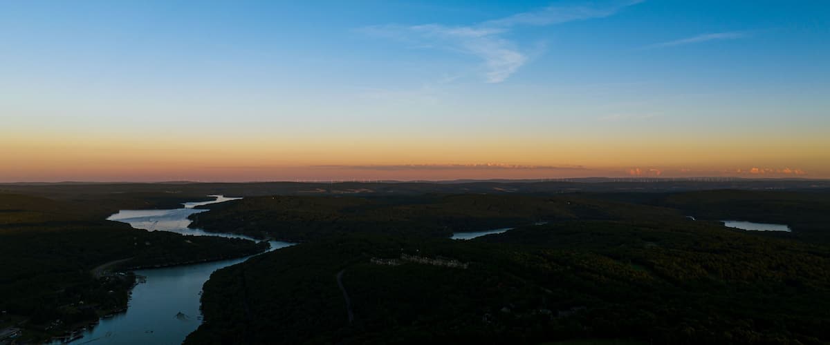 A river winding through a forested landscape with a clear sky.