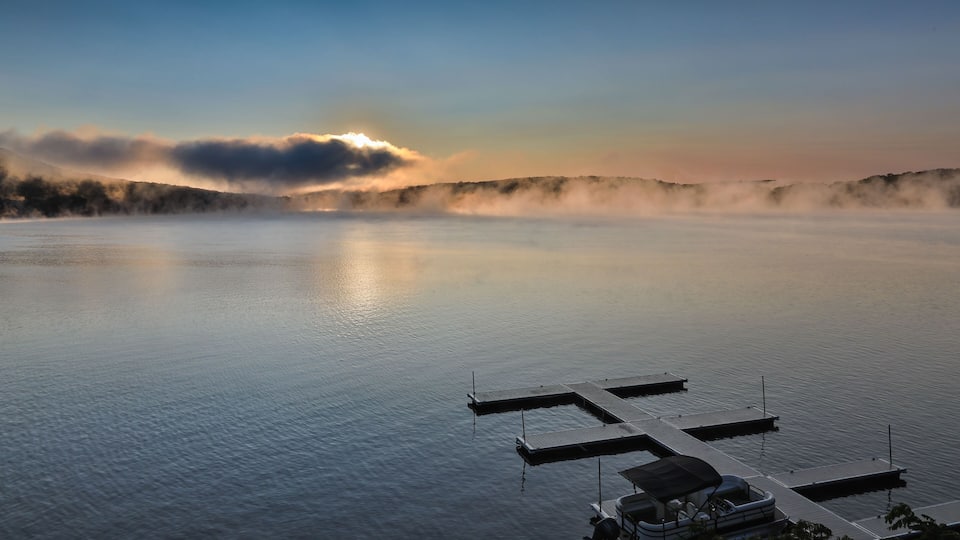 A calm lake with a dock and a boat.