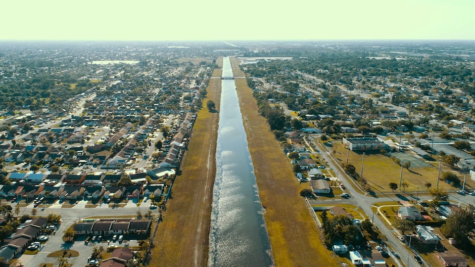 An aerial view of a residential area with a long, narrow water body running through it.
