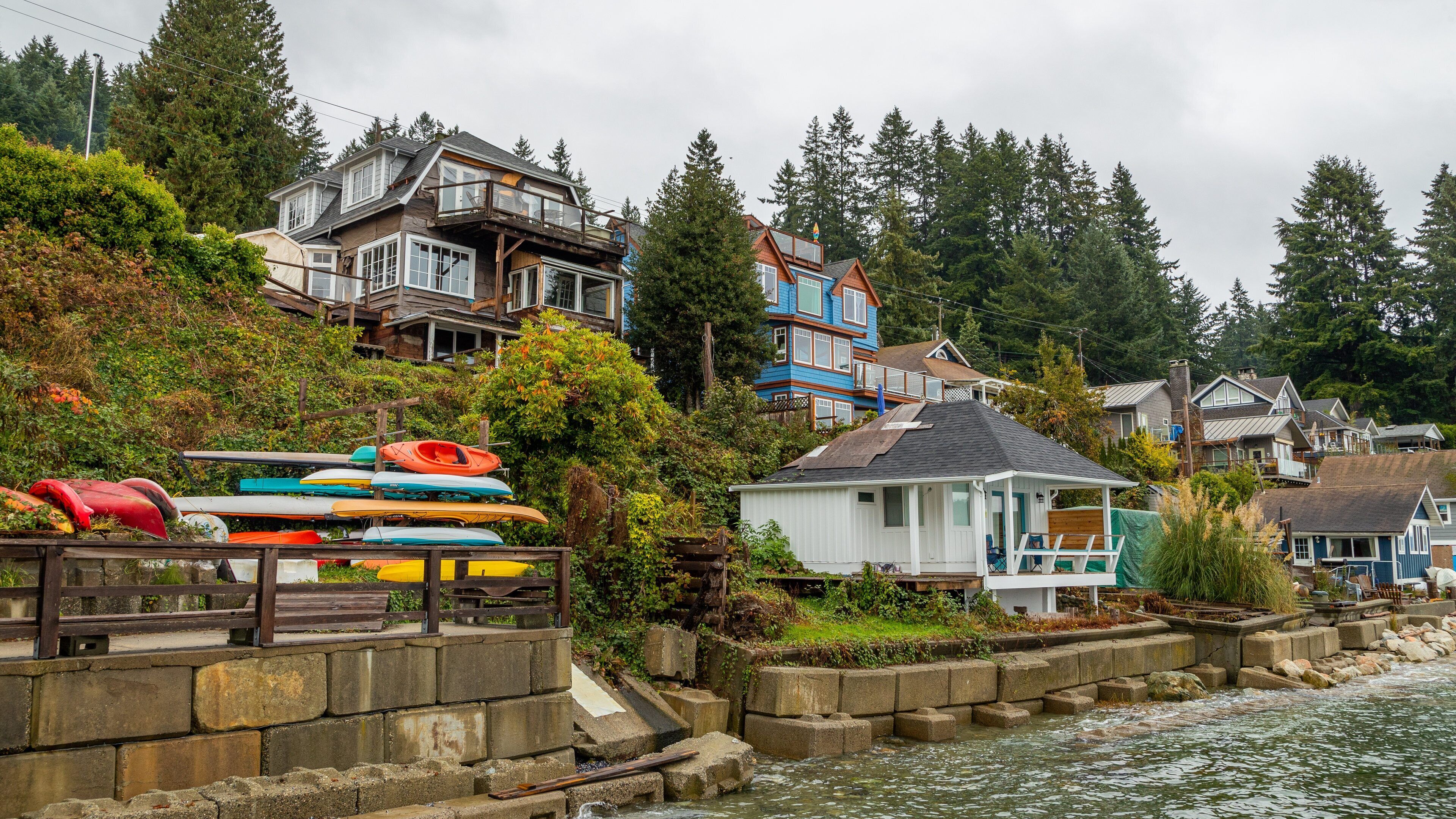 A waterfront with houses, kayaks, and a small dock.