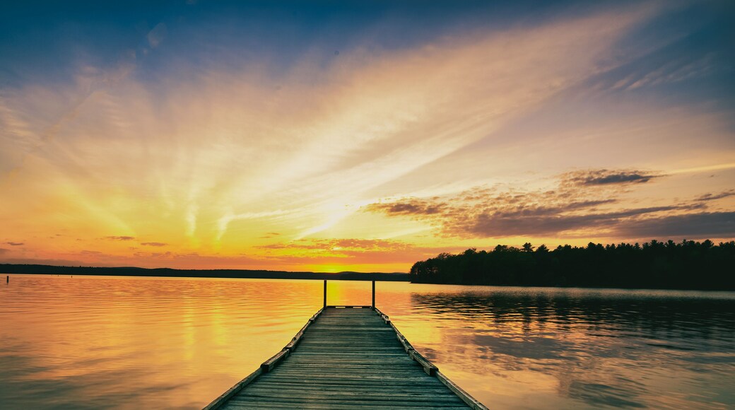 summer sunset over the lake looking at the fishing dock and the forest on the horizon