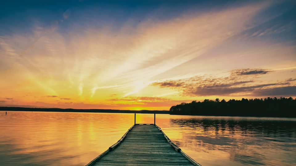 summer sunset over the lake looking at the fishing dock and the forest on the horizon