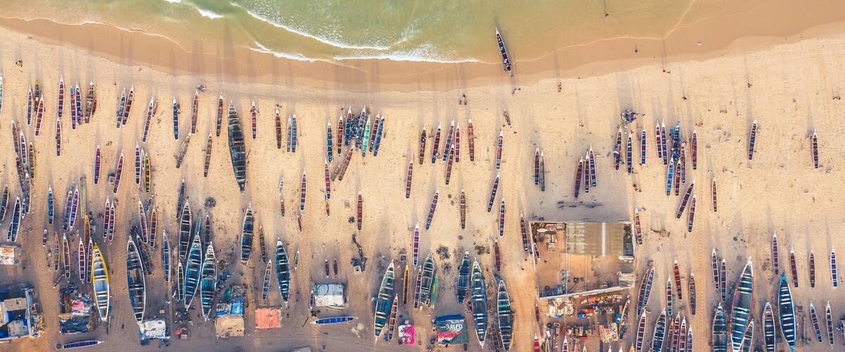 A beach with rows of boats and a sandy shoreline.
