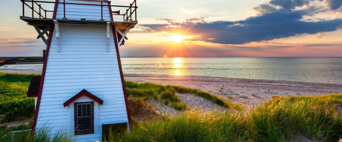 A lighthouse by the sea at sunset.