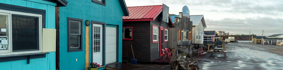 A stripmall with simple buildings housing restaurants, vendors and services for local harbor visitors along a paved parking area, Covehead Harbour, Prince Edward Island, Canada