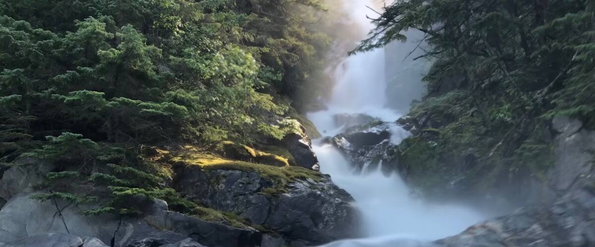 A waterfall cascading over rocks in a forested area.