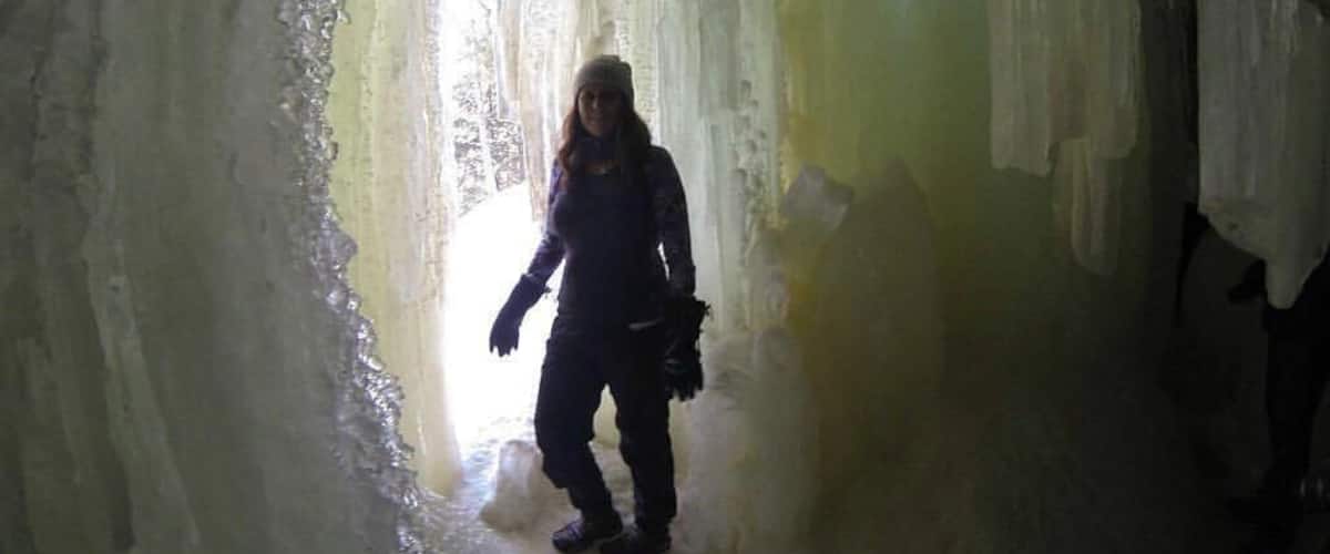 A person walking through a cave with ice formations.