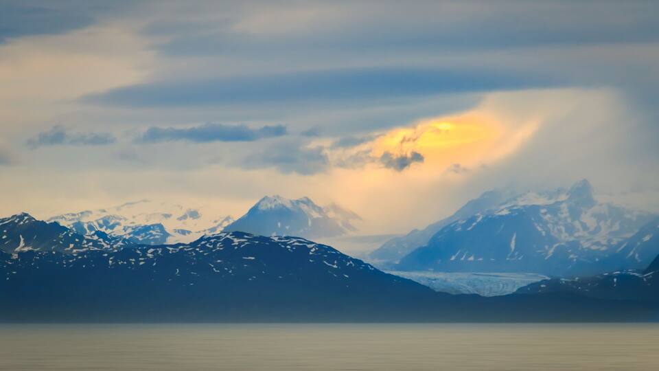 A mountain range with snow-capped peaks and a glacier.
