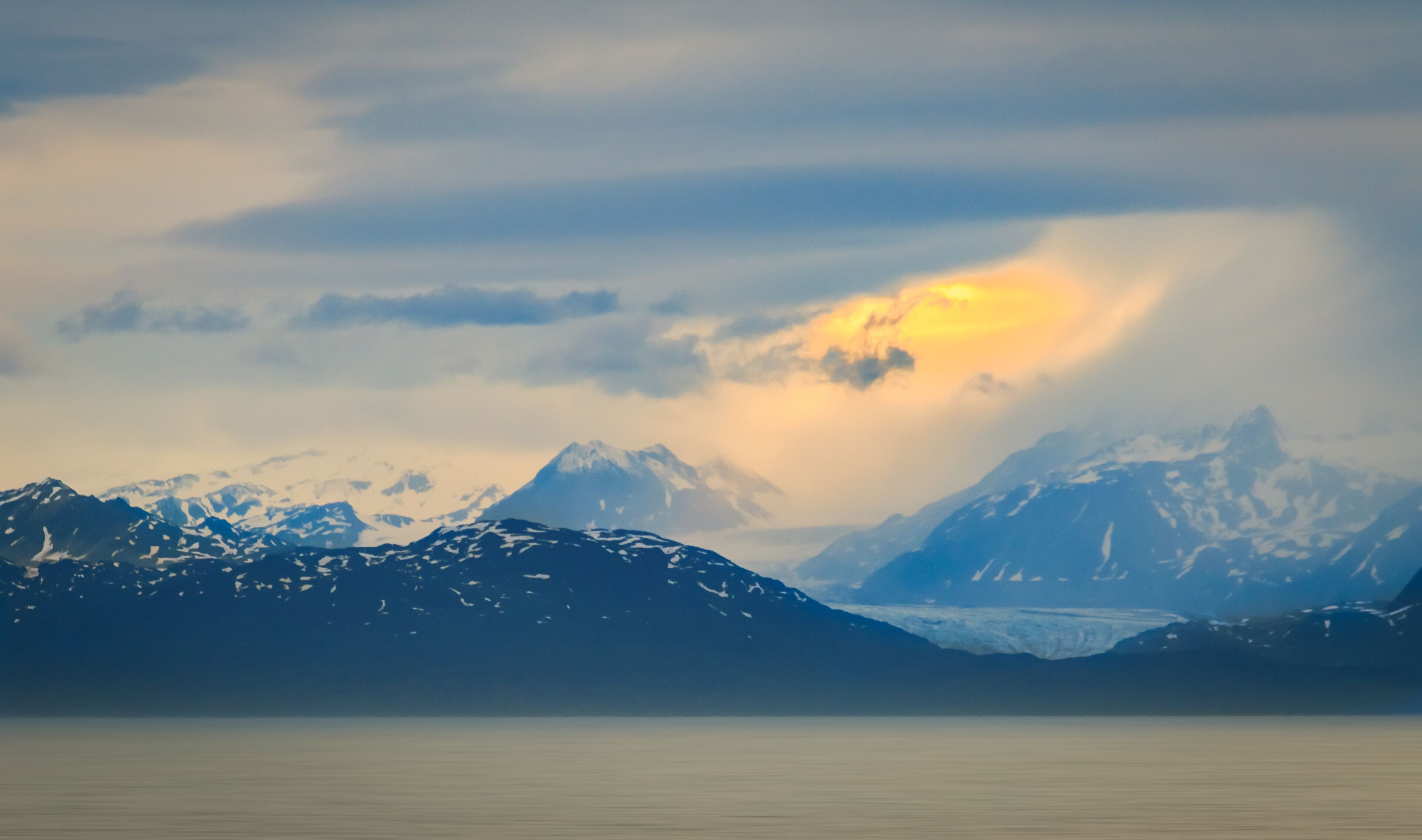A mountain range with snow-capped peaks and a glacier.