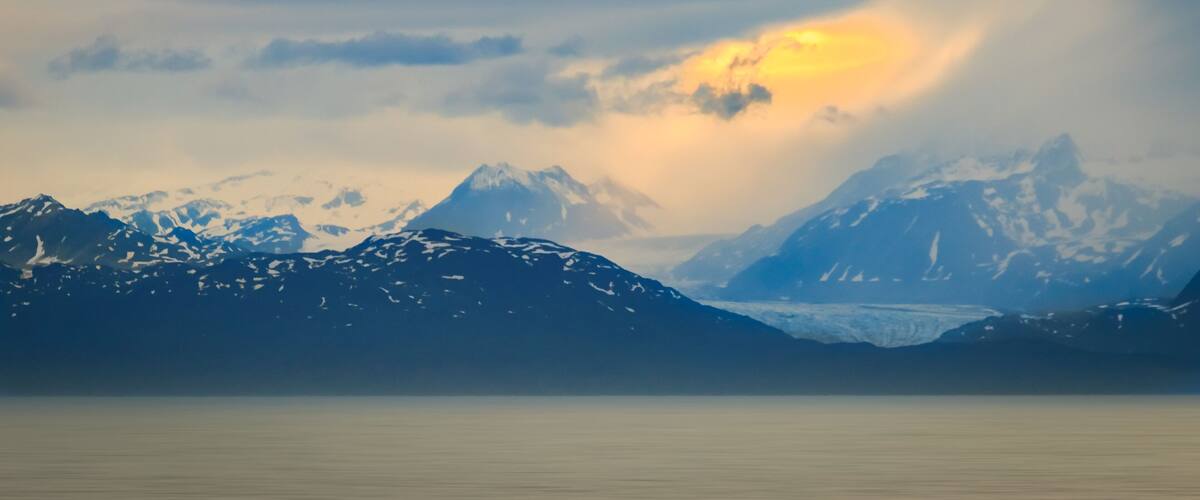 A mountain range with snow-capped peaks and a glacier.