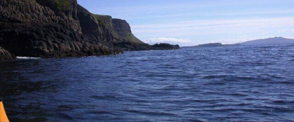 A coastal landscape with steep cliffs and calm sea.