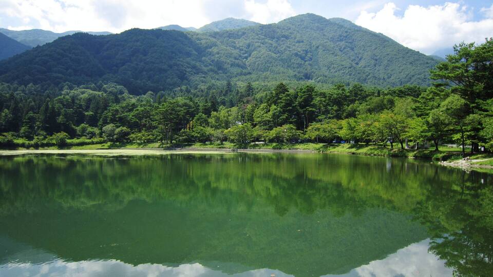 A calm lake surrounded by lush green hills and trees.