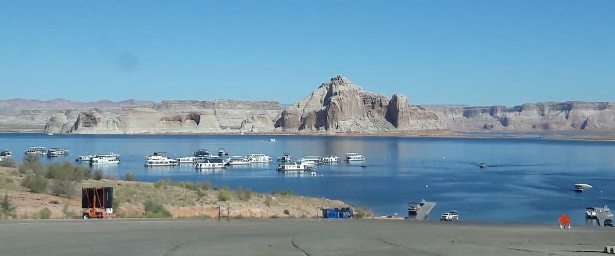 A large body of water with boats, a rocky mountain, and a clear sky.