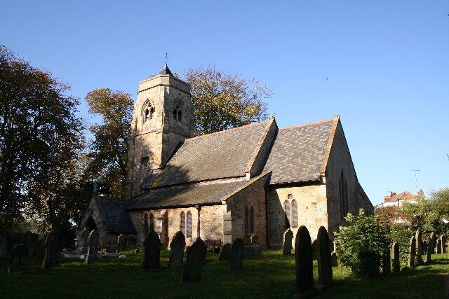 A historic church with a bell tower and a cemetery in the foreground.