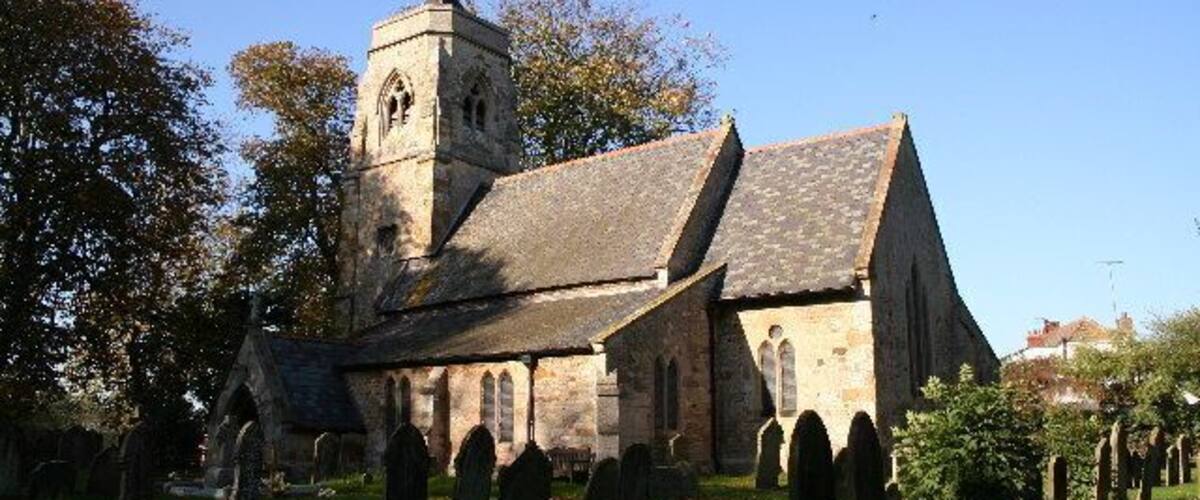 A historic church with a bell tower and a cemetery in the foreground.