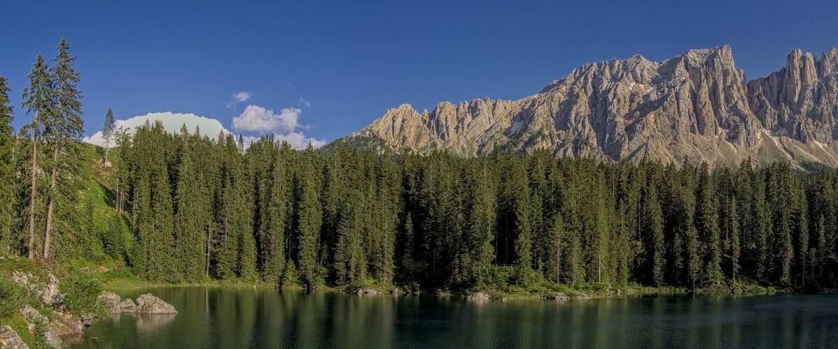 A mountain range with dense forests and a calm lake.