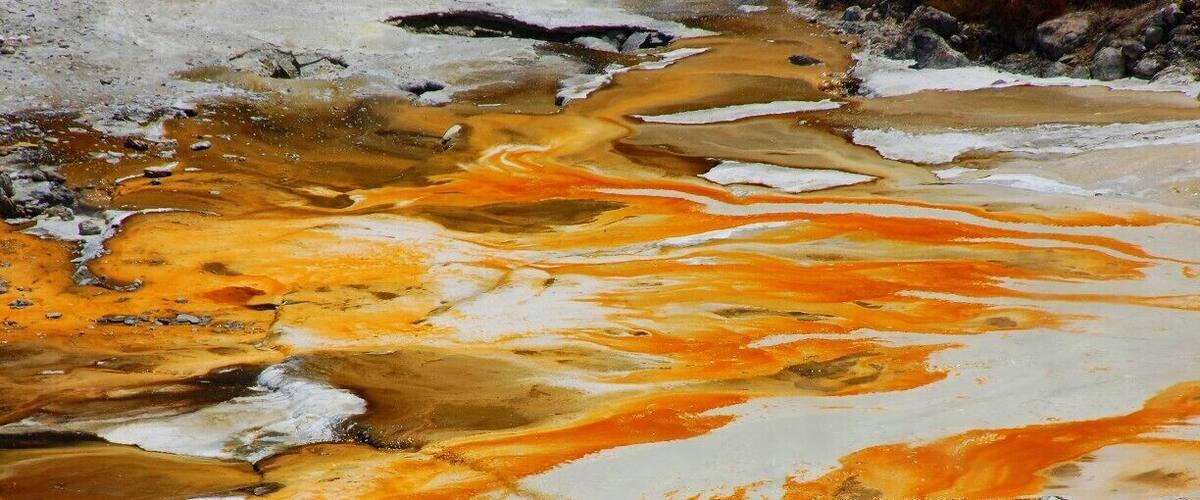 A geothermal pool with orange and white mineral deposits.