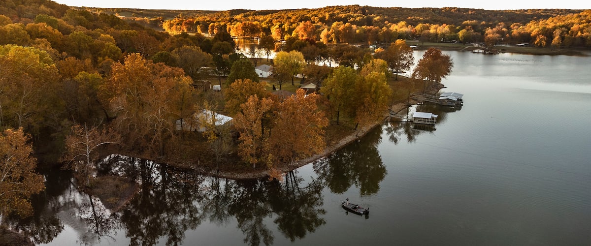 A river with a small island of trees and buildings.
