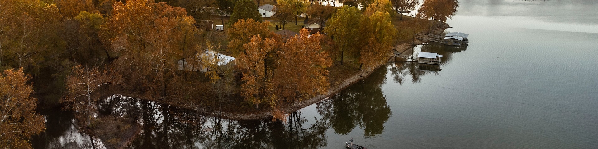 A river with a small island of trees and buildings.