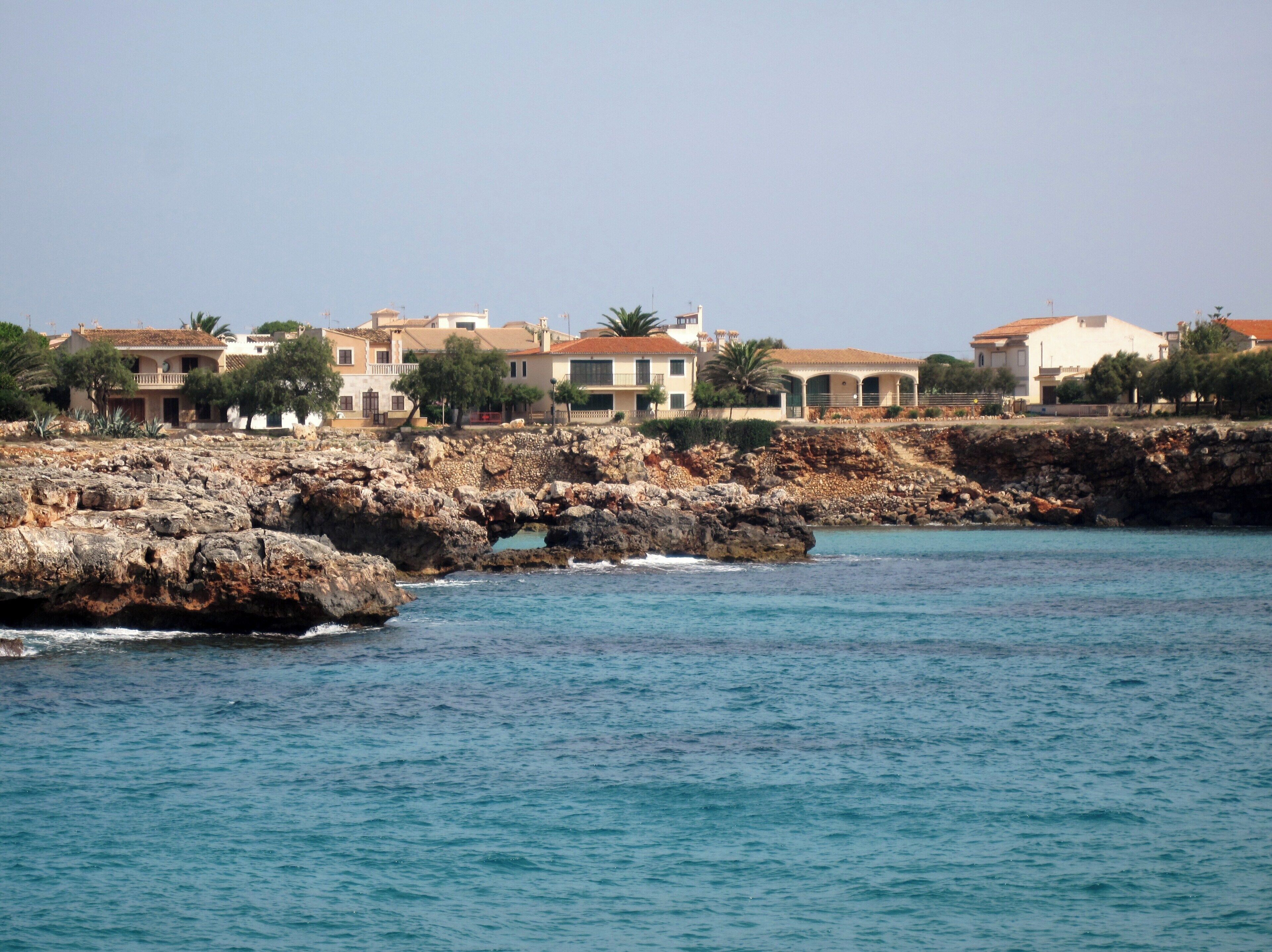 A coastal town with rocky cliffs and buildings along the shoreline.