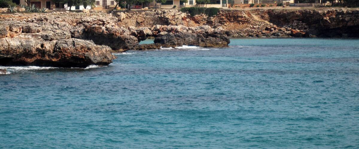 A coastal town with rocky cliffs and buildings along the shoreline.