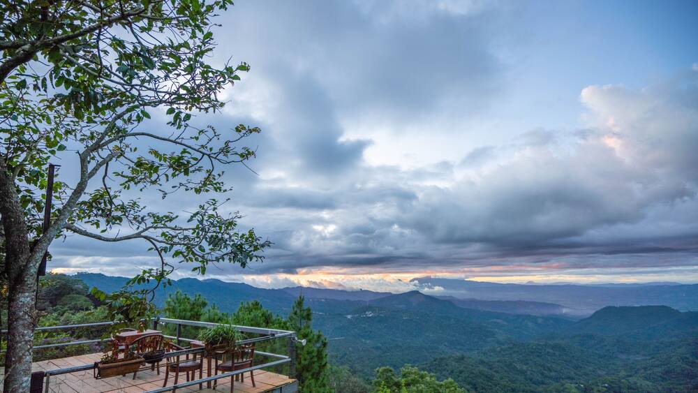 A wooden deck with chairs overlooking a mountainous landscape.