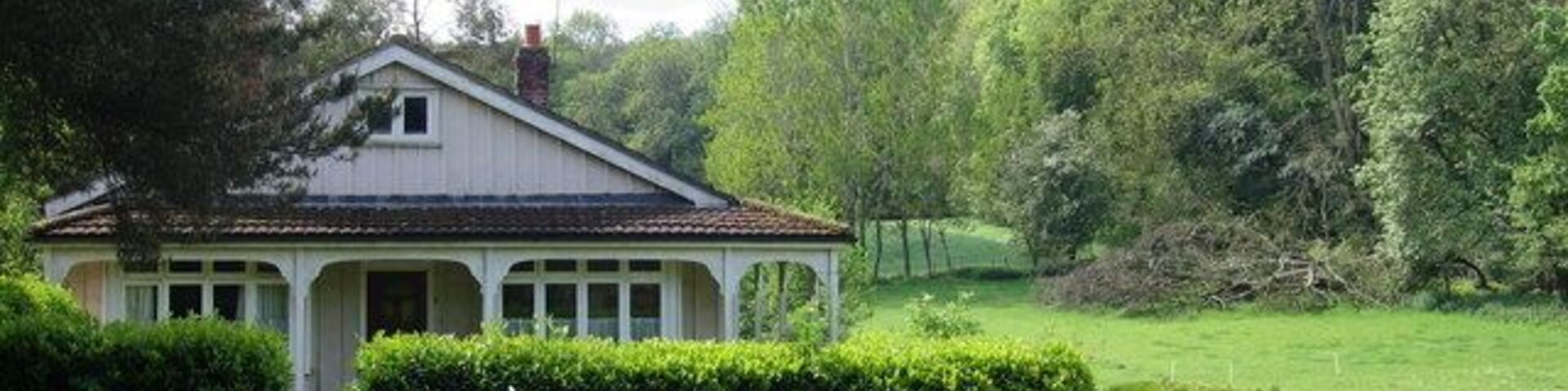 Una casa blanca con techo rojo rodeada de exuberante césped verde y árboles.