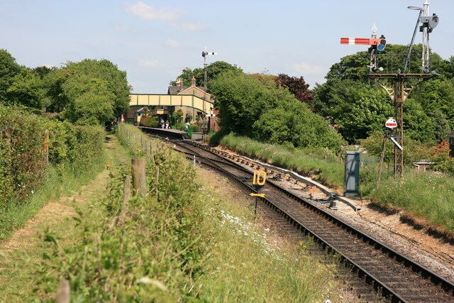 A railway track with a signal box and a building in the background.