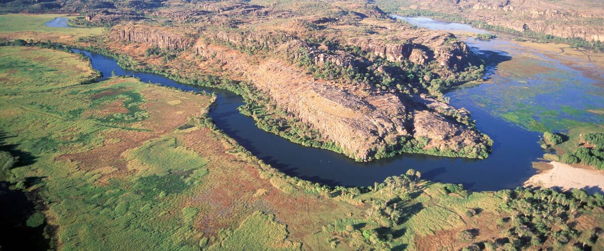 A river winding through a rugged landscape with green vegetation and rocky outcrops.