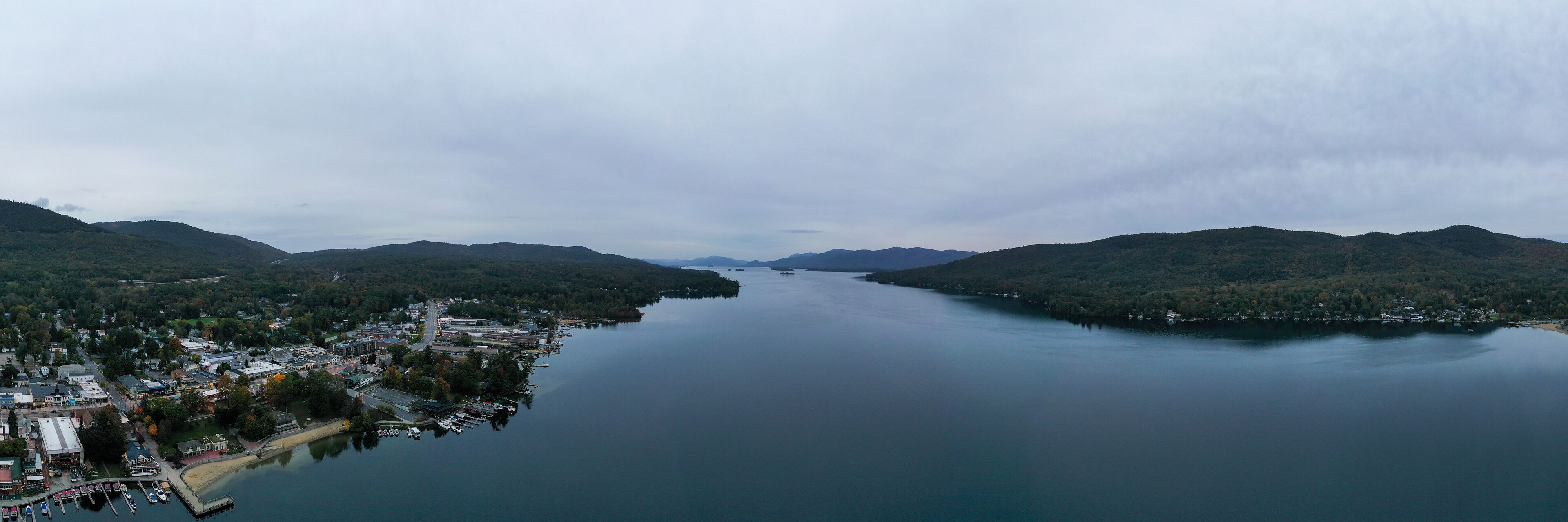 A lake surrounded by hills with a small town and docked boats.