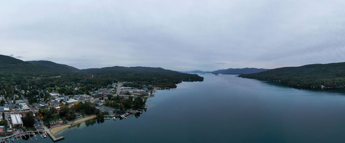 A lake surrounded by hills with a small town and docked boats.