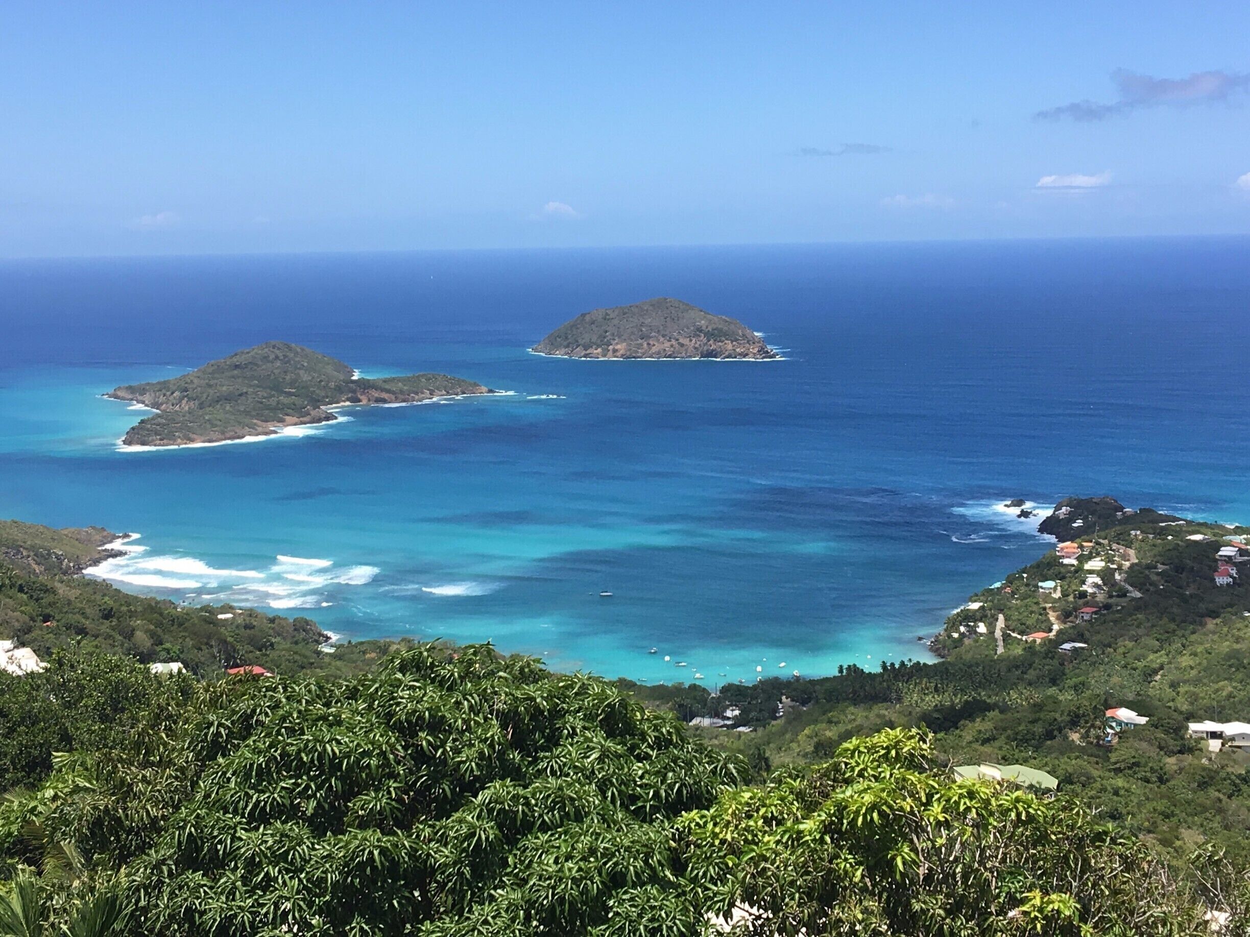 A coastal landscape with two small islands surrounded by turquoise waters.
