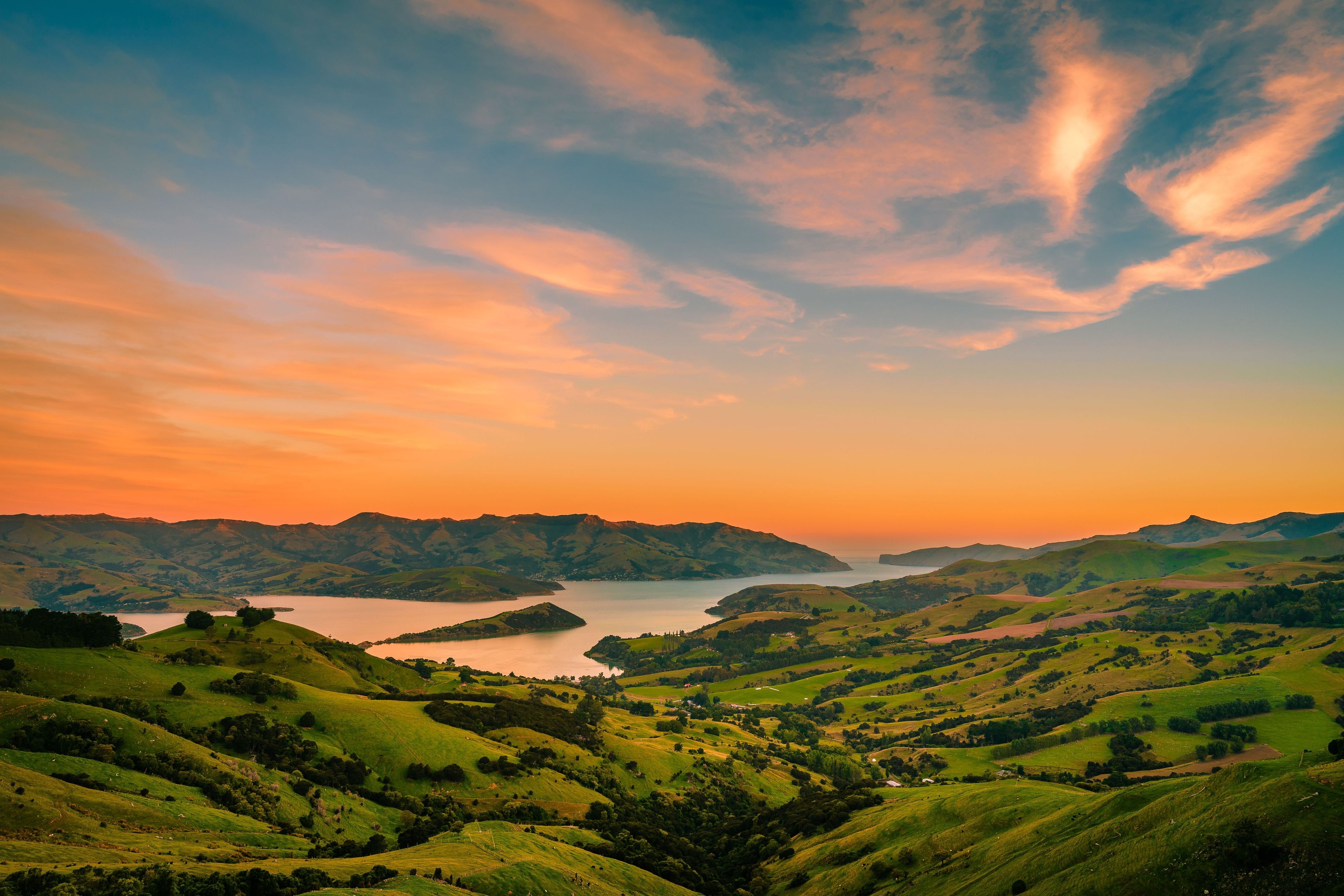Rolling green hills, a lake, and a sunset sky.