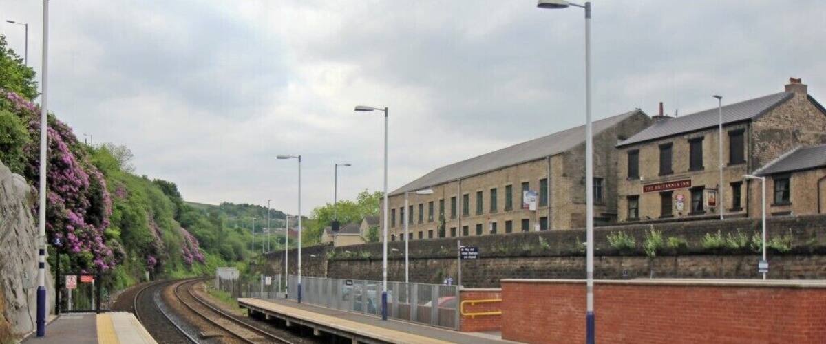 A railway station platform with tracks, a brick wall, and a building labeled "The Britannian."